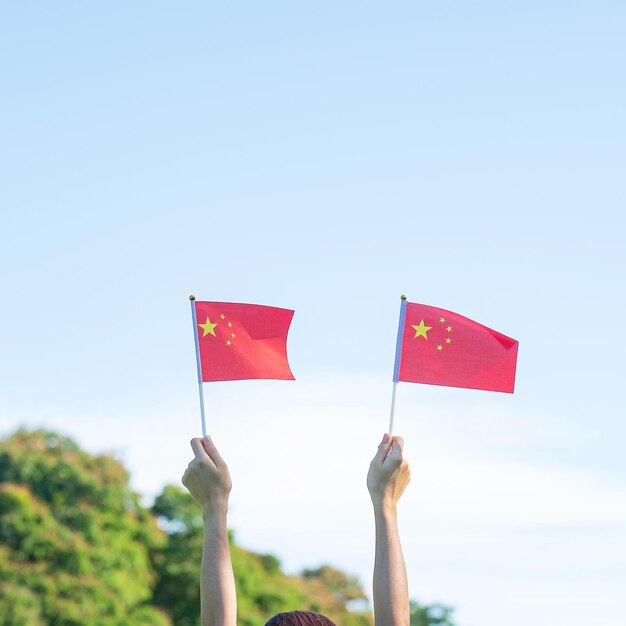 Hand holding China flag on blue sky background National Day of the People Republic of China public Nation holiday Day and happy celebration concepts