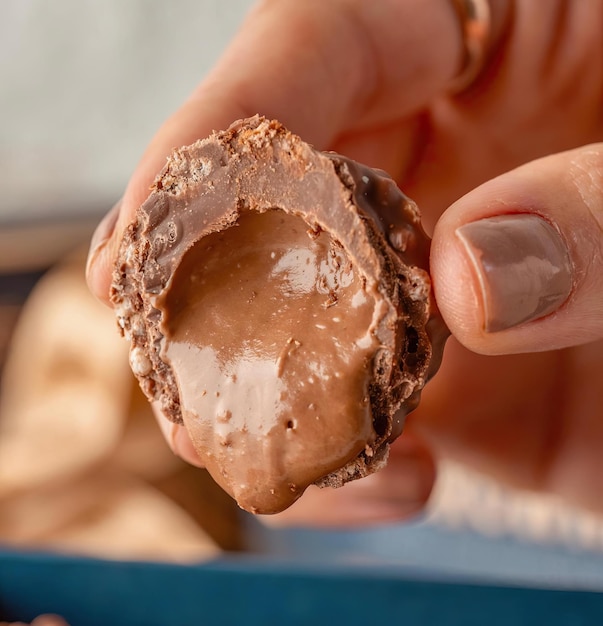 A hand holding a chocolate truffle with the word chocolate on it.