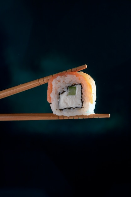 Hand holding chopstick to eat Sushi