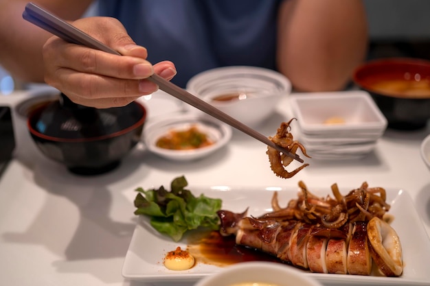 イカの触手を食べる箸を持っている手