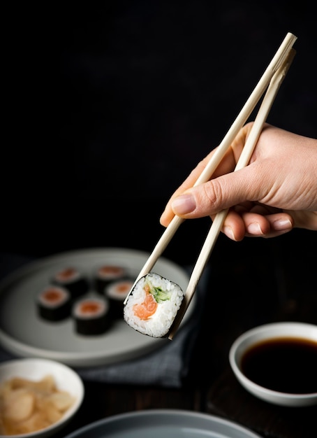 Hand holding chopsticks for sushi rolls