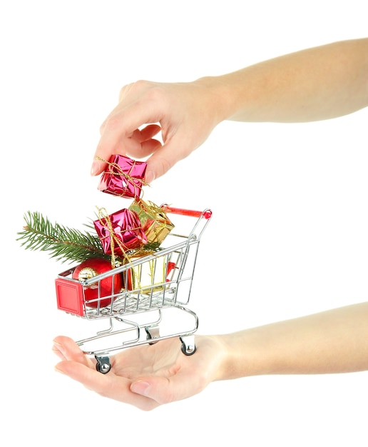 Hand holding Christmas gifts in shopping trolley, isolated on white