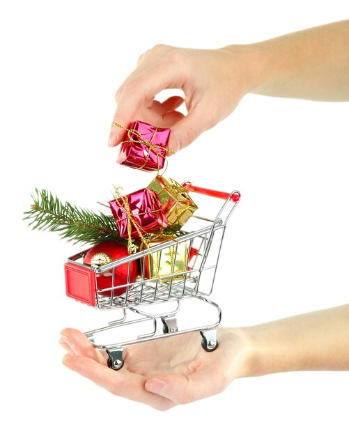 Hand holding Christmas gifts in shopping trolley, isolated on white