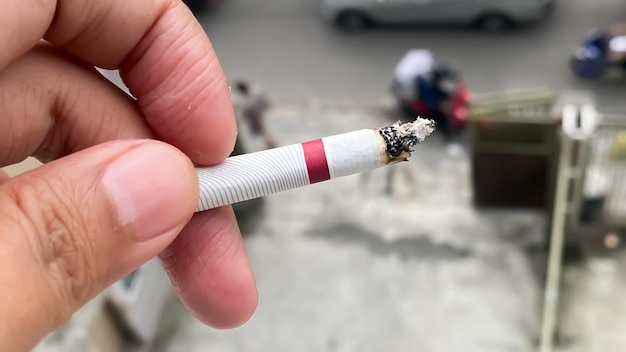 A hand holding a cigarette with a red stripe that says'smoking'on it