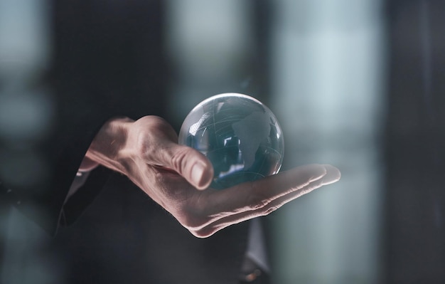 Photo hand holding a clear transparent crystal glass ball isolated on black background