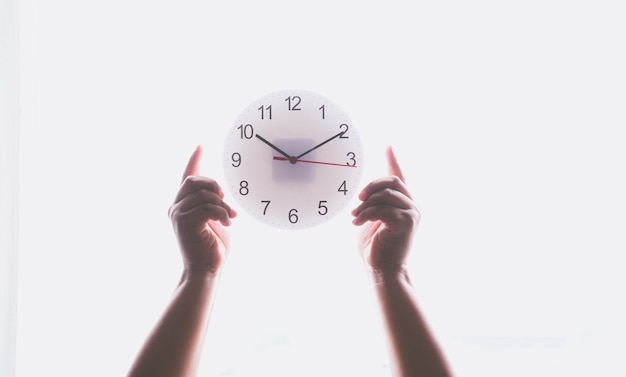 Photo hand holding a clock on blurred background