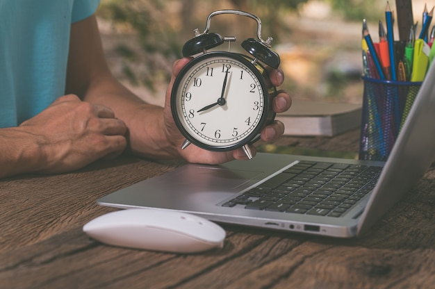 The hand holding the clock is at the work desk