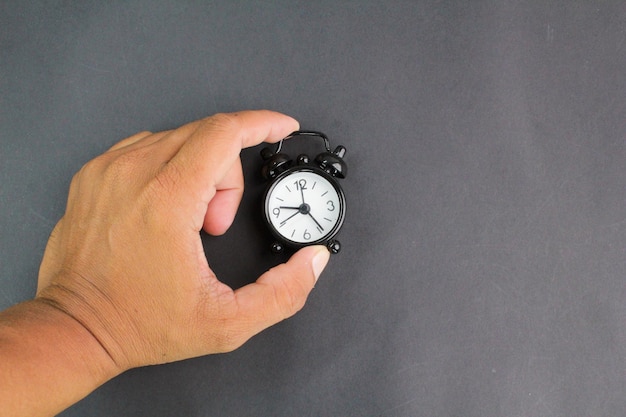 A hand holding a clock that says the time is 1 30