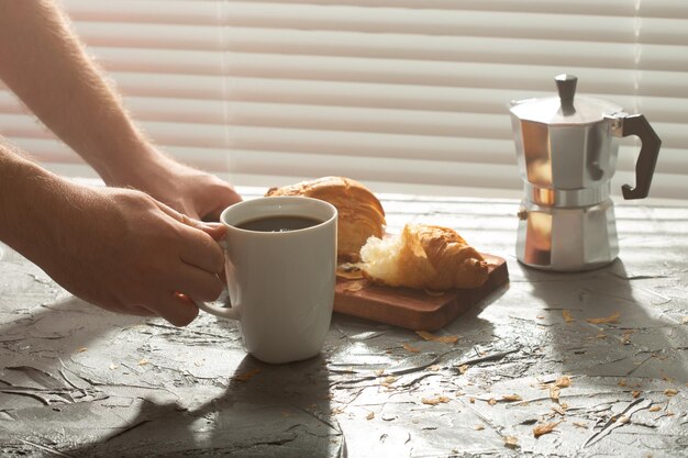 写真 手でコーヒーカップとスプーンをテーブルに置く