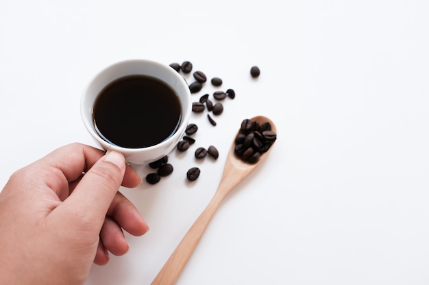 Foto passi la tazza e i fagioli di caffè della holding su una priorità bassa bianca