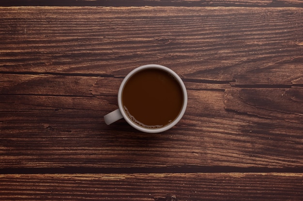 Hand holding a coffee mug on a wood background