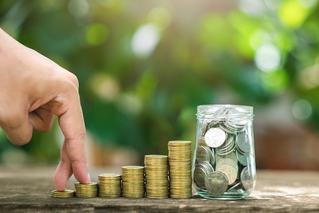 Photo hand holding coin on coins stacks