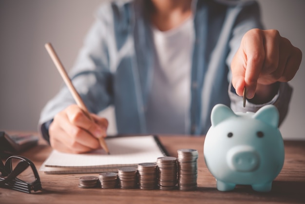 Hand holding coin with pig piggy bank. Saving and financial accounts concept