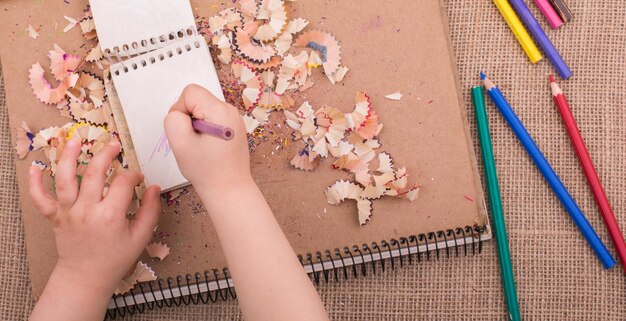 Photo hand holding a color pencil on spiral notebooks