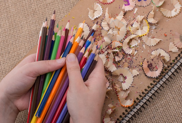 Hand holding Color Pencils over a notebook