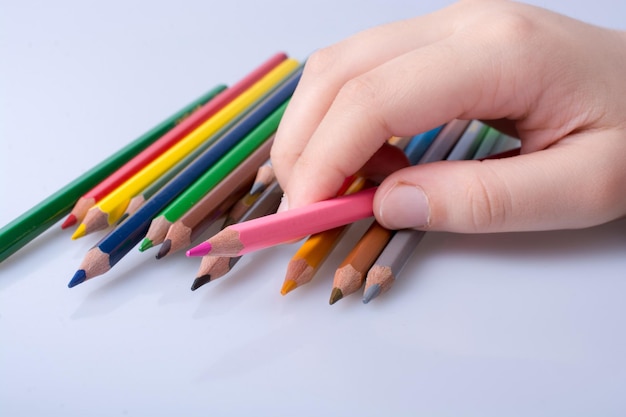 Hand holding color pencils placed on a white background