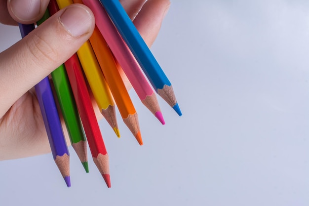 Hand holding color Pencils placed on a white background