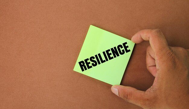 hand holding colored paper with the word resilience