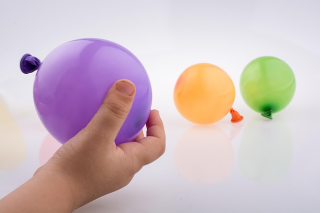 Hand holding a colorful small balloon with colorful baloons on the white background