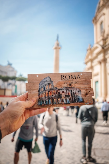 Photo hand holding colosseum postcard aligned with bustling rome street