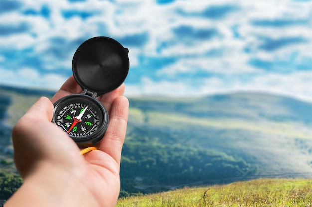 Photo hand holding the compass on background.