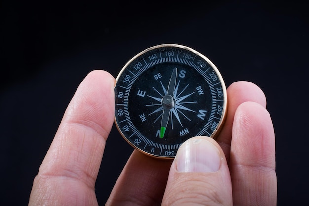 Hand holding a compass on black background