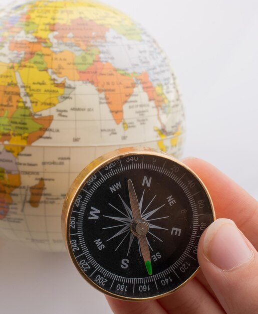 Hand holding a compass and a globe