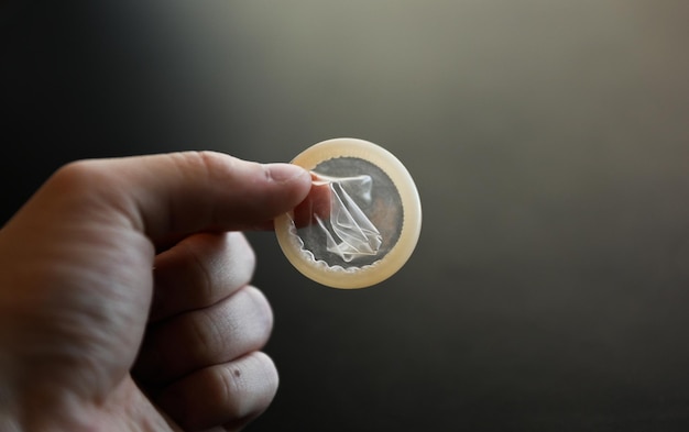 Hand holding condom with HIV and safe sex wrappers in background Promoting safe sex and protection