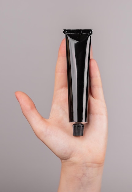 Hand holding cream tube mockup Skin care cosmetics concept Black template