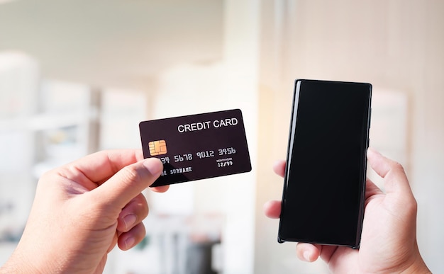 Hand holding a credit card and blank screen of mobile phone online shopping concept