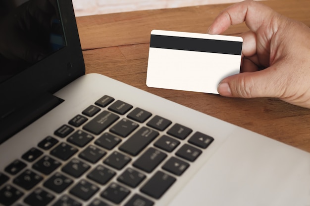 Hand holding credit card on laptop for online shopping concept.