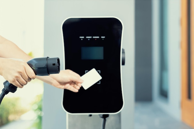 Hand holding credit card and pay charging station to progressive EV car