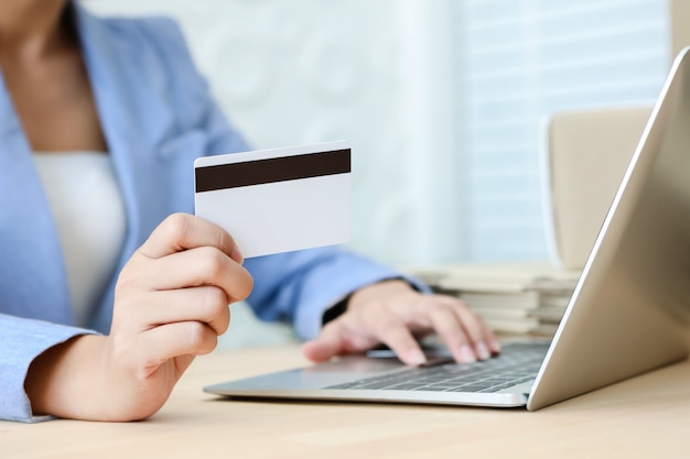 Hand holding credit card typing on the keyboard of laptop