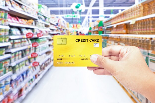 Photo hand holding credit card with supermarket background