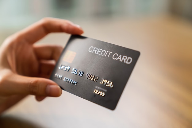 Hand holding credit card on wood table.