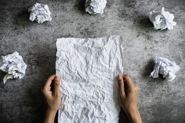 Hand holding crumpled paper on table