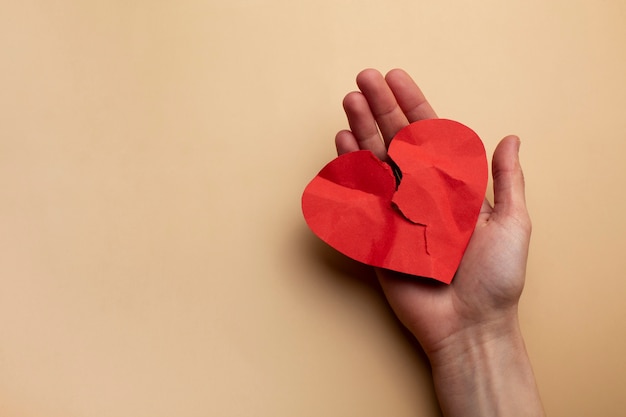 Photo hand holding crumpled red heart top view