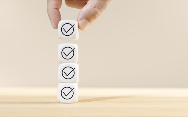 Hand holding a cube block on top of other blocks stacked with check icon Checking concept