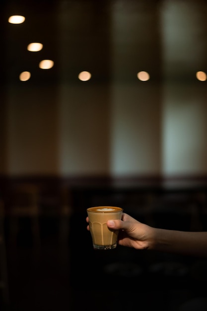 A hand holding a cup of coffee in a dark room