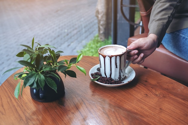 hand holding a cup of hot chocolate on wooden table in cafe