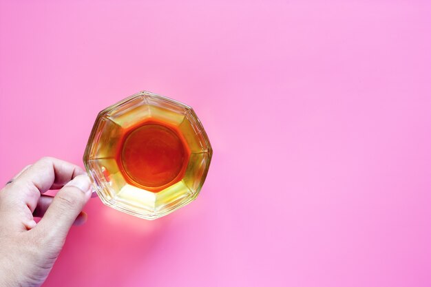 Hand holding cup of tea on pink background for drinks and beverage concept