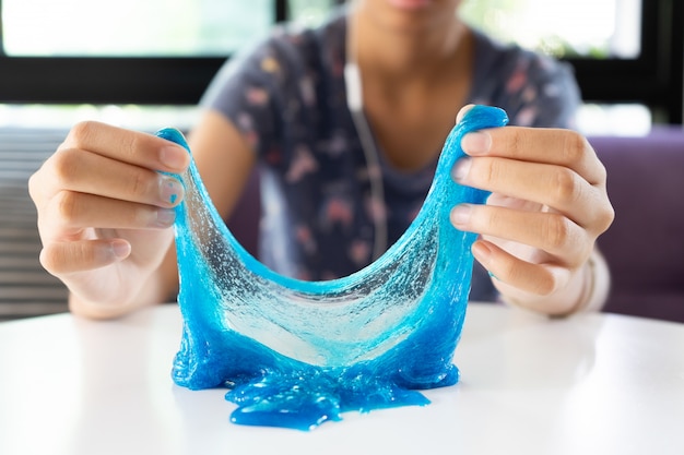Photo hand holding dark blue slime on white table