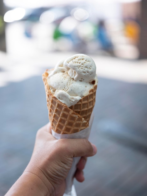 Photo hand holding delicious crispy waffle cone of milk ice cream