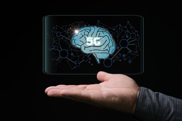 Hand holding design of 5G text on a brain on dark background