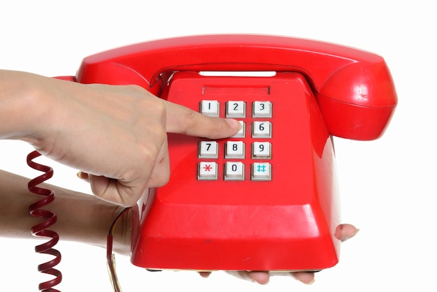 hand holding and dialing old telephone against white wall