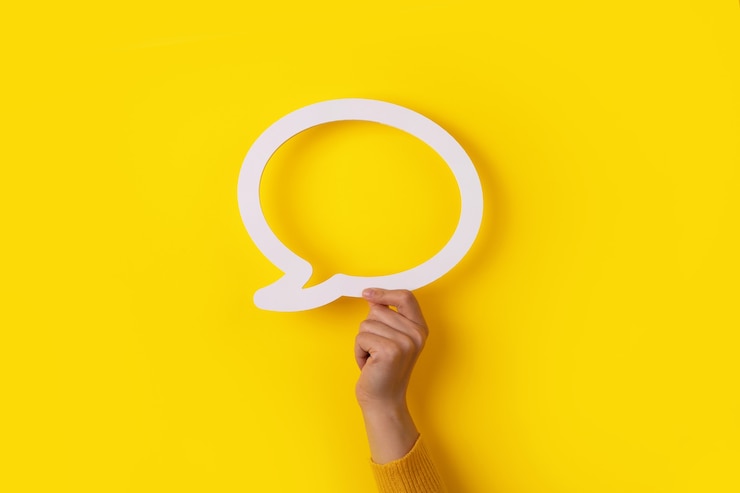 Photo hand holding dialogue bubble over yellow background