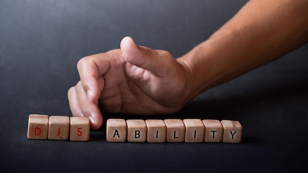 Hand holding dice with text for illustration of ABILITY or DISABILITY words