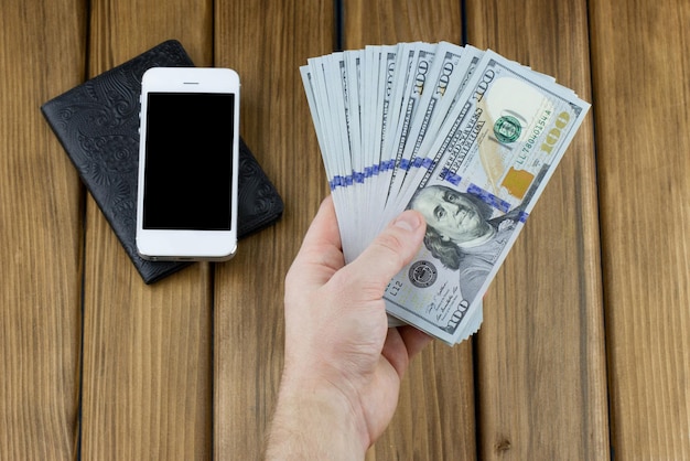 Hand holding dollar bills with smartphone