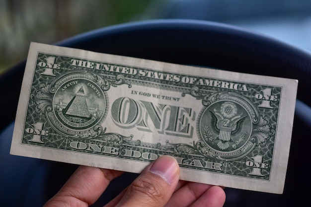 Hand holding dollar in car