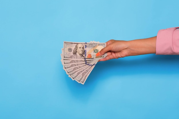 Hand holding dollar currency over blue background